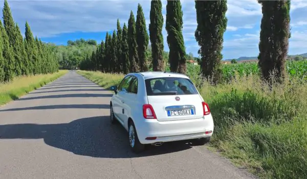 road-trip-italy-europe White Fiat 500 on a road trip in Tuscany Italy with typical landscape