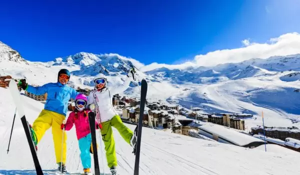 family-ski-france Happy family skiing in the French Alps with blue sky and lots of snow in the background